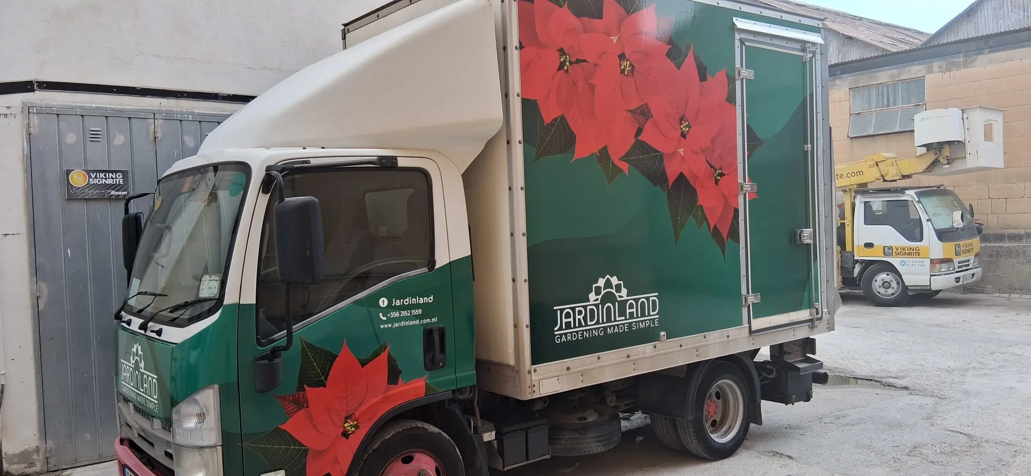 Box truck wrapped in deep green with large printed poinsettia flowers along the body