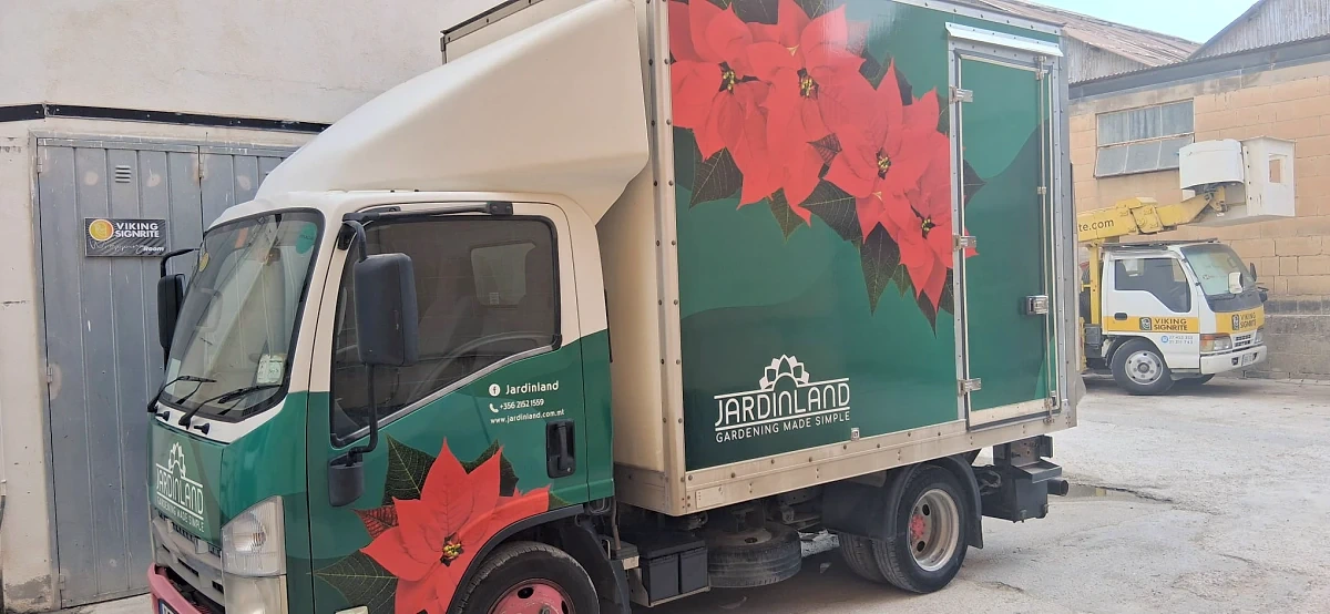 Box truck wrapped in deep green with large printed poinsettia flowers along the body