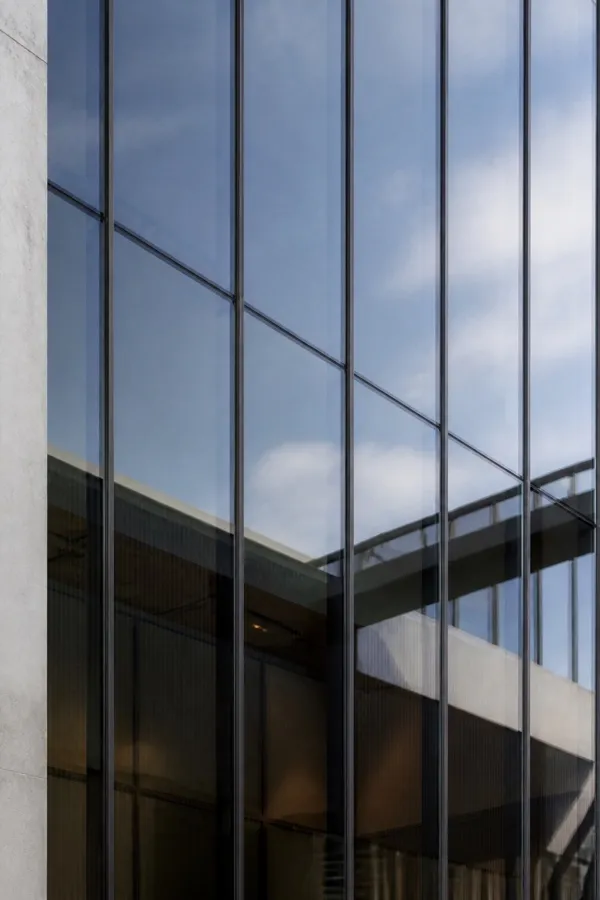 Solar-control glazed facade reflecting clouds and surrounding architecture