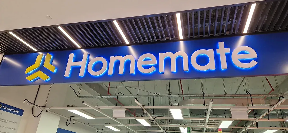 Illuminated blue interior sign with white built-up lettering above a store aisle