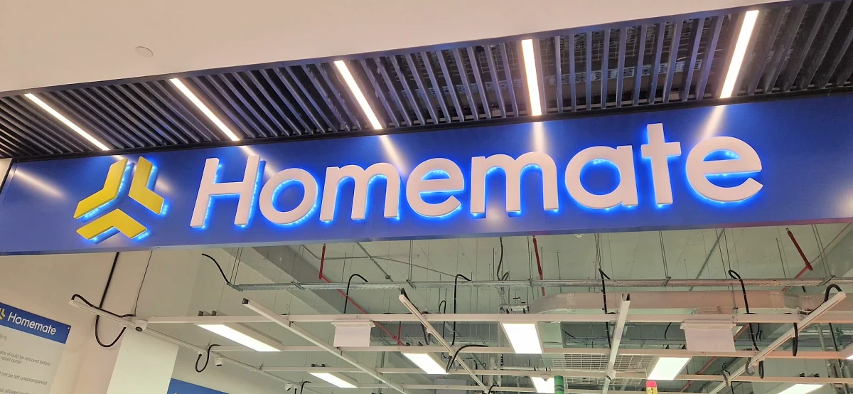 Illuminated blue interior sign with white built-up lettering above a store aisle