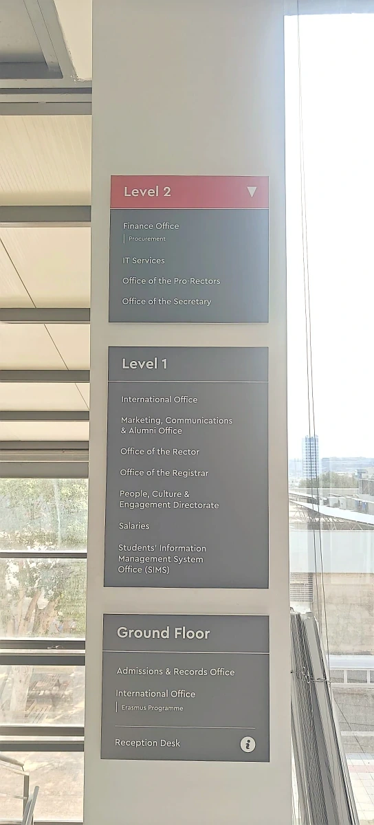 Three stacked directory panels listing the offices on each floor beside a glazed stairwell