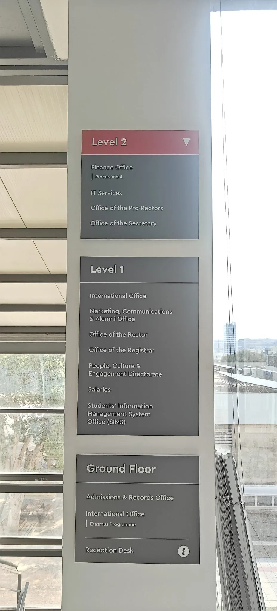 Three stacked directory panels listing the offices on each floor beside a glazed stairwell