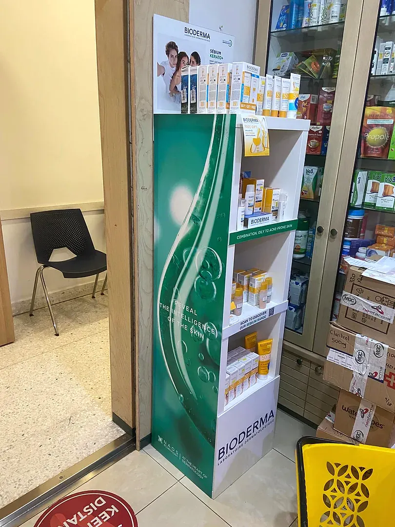 Free-standing four-shelf retail display stocked with skincare cartons in a pharmacy