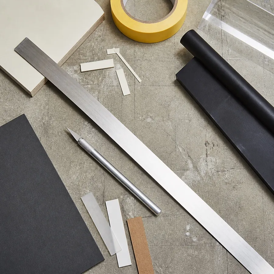 Steel rule, precision knife, squeegee and tape arranged on a fabrication bench