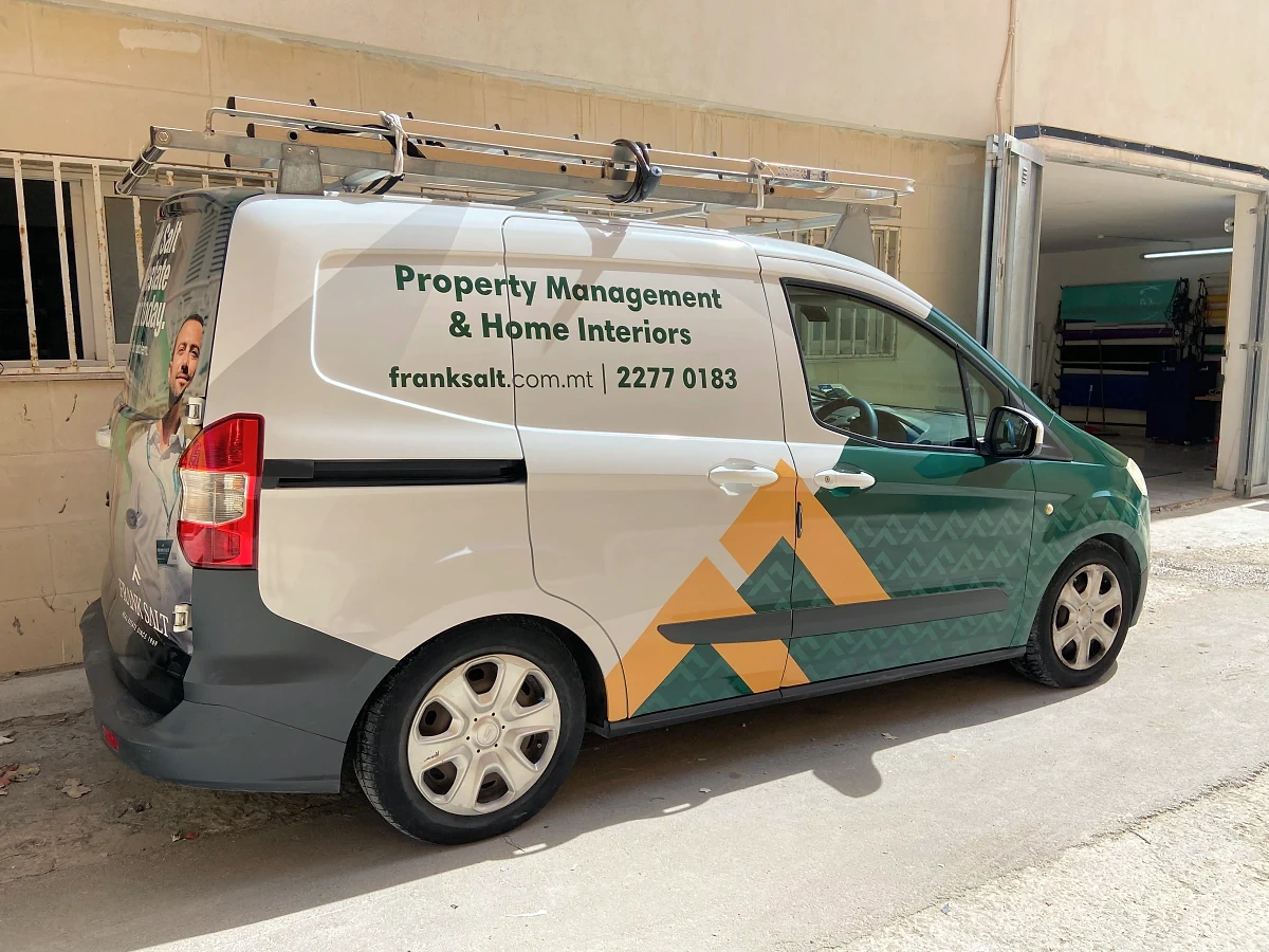 Small van in green and white livery with a geometric pattern and a roof rack