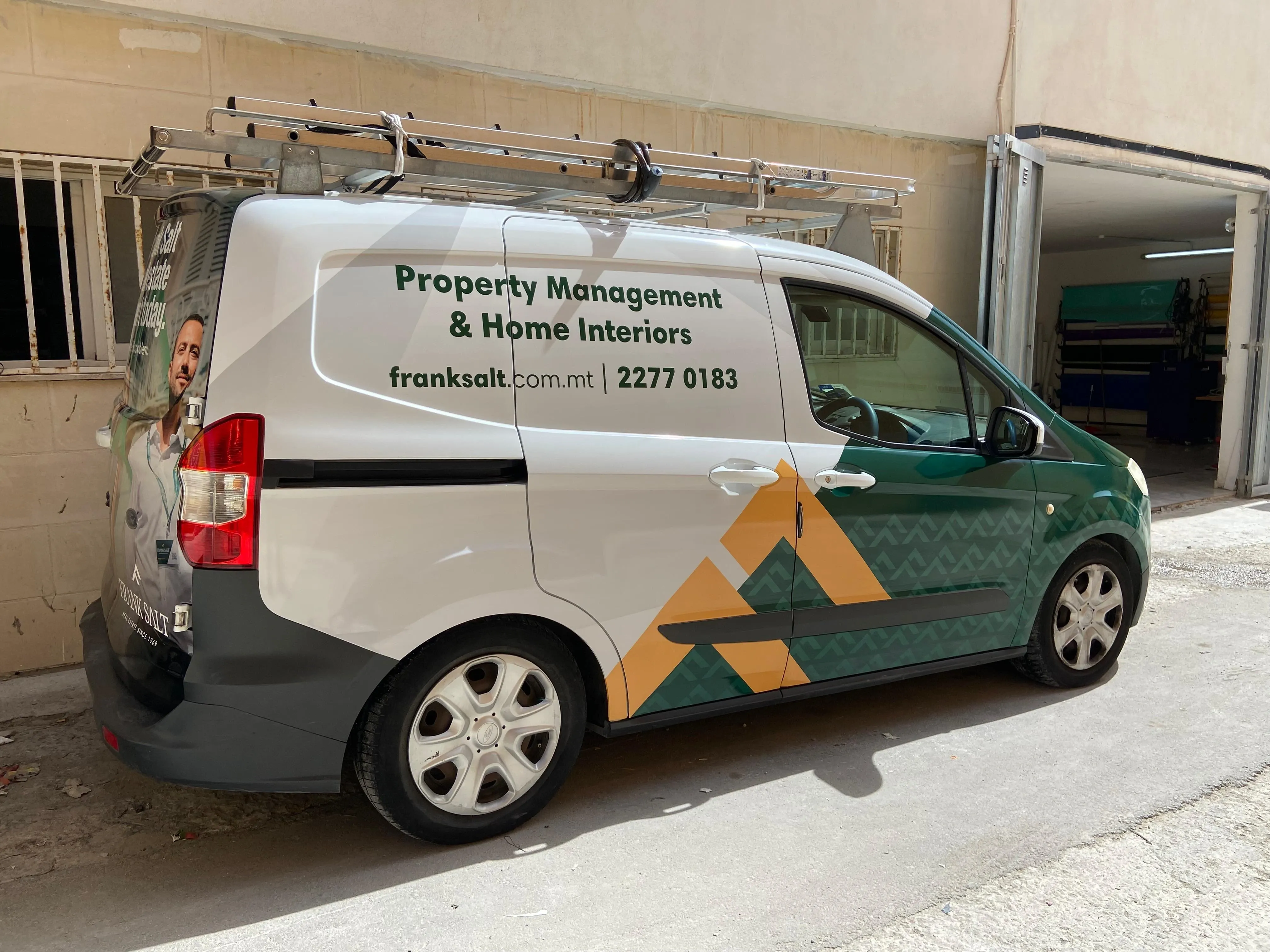 Small van in green and white livery with a geometric pattern and a roof rack