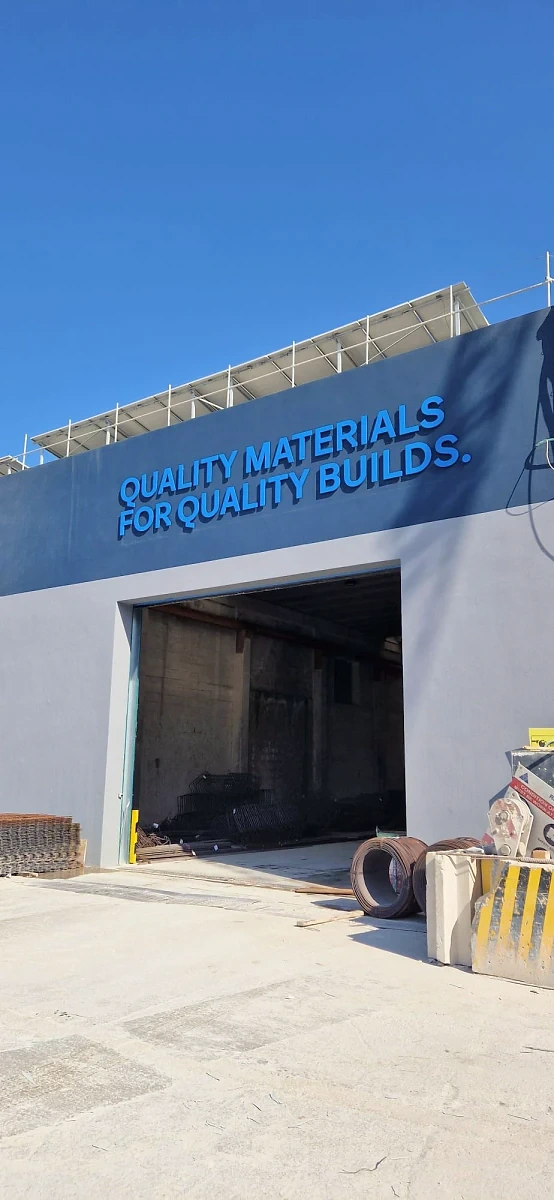 Blue built-up lettering reading quality materials for quality builds across an industrial facade