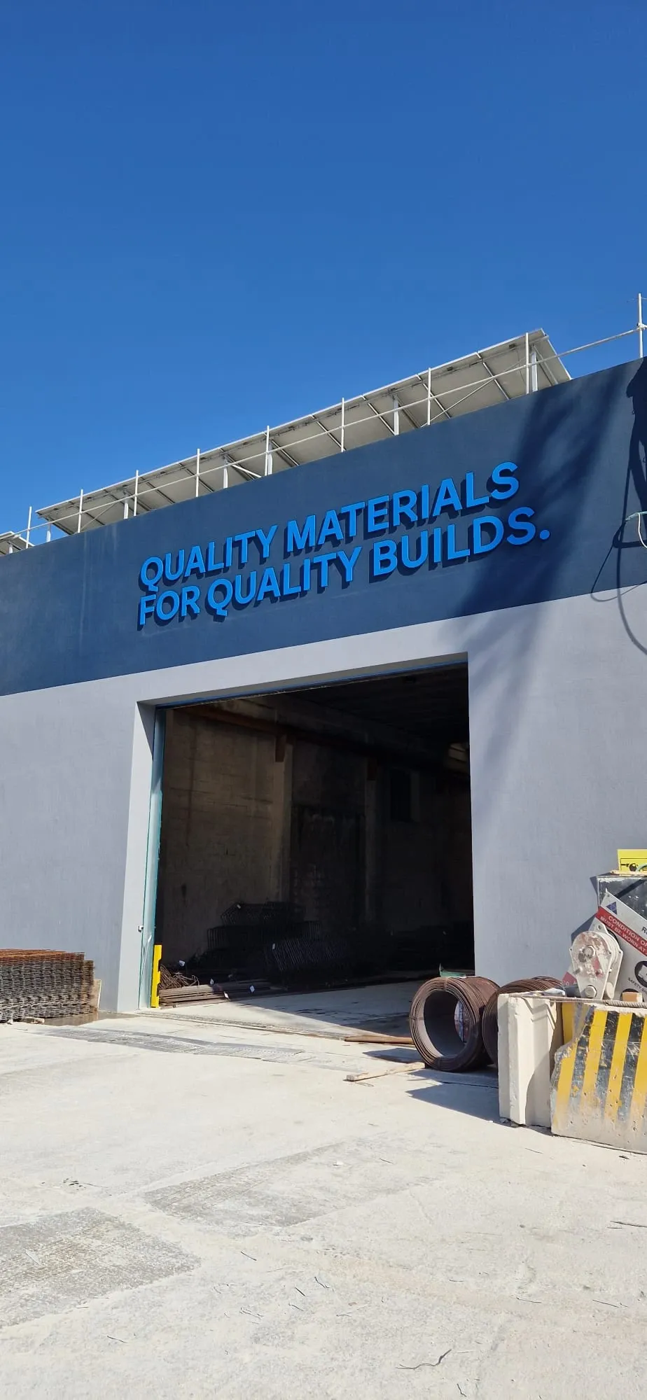 Blue built-up lettering reading quality materials for quality builds across an industrial facade