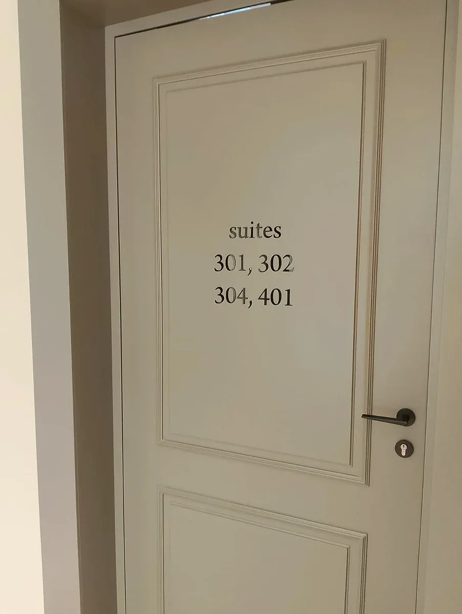 Cut vinyl suite numbers applied to a panelled cream door