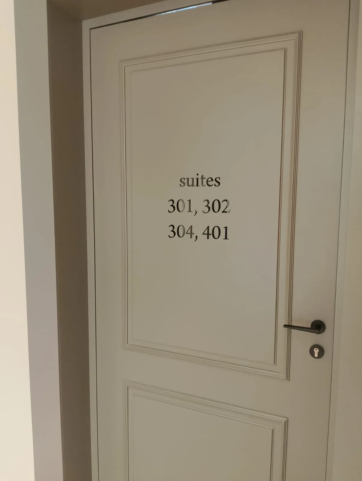 Cut vinyl suite numbers applied to a panelled cream door
