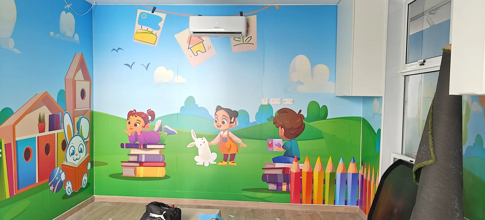 Children's playroom with printed wall murals of characters, books and oversized pencils