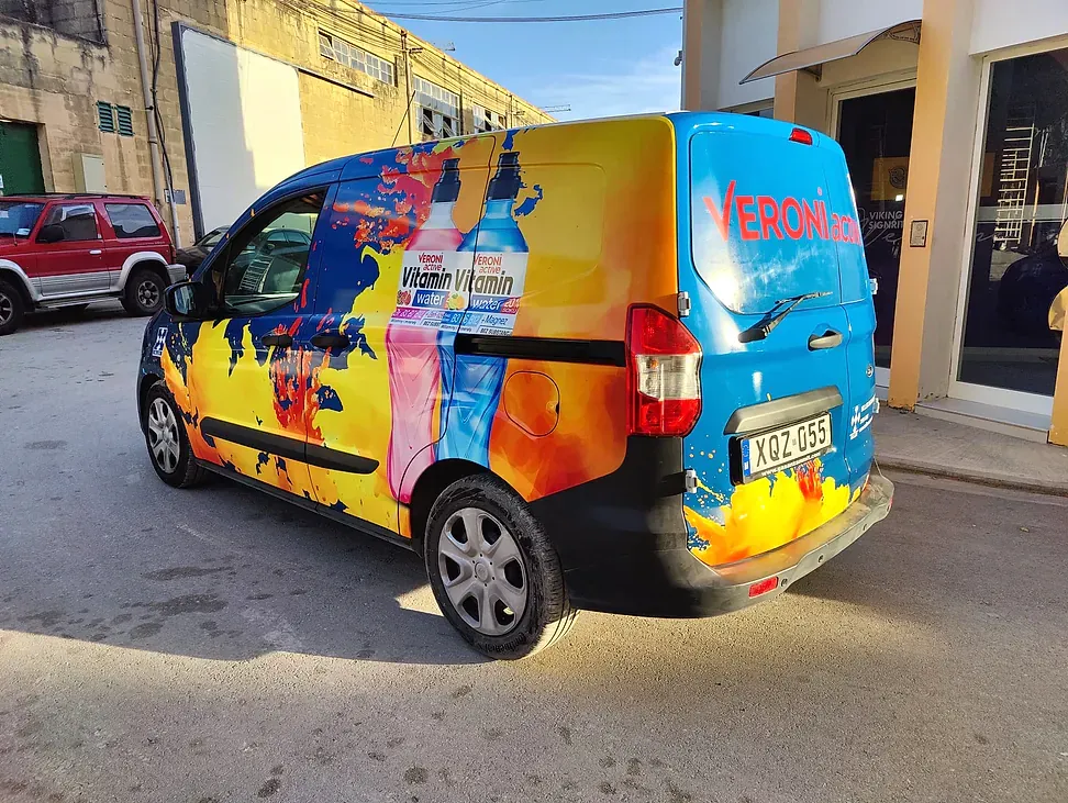 Compact van wrapped in a bright orange and blue pattern with printed drink bottles