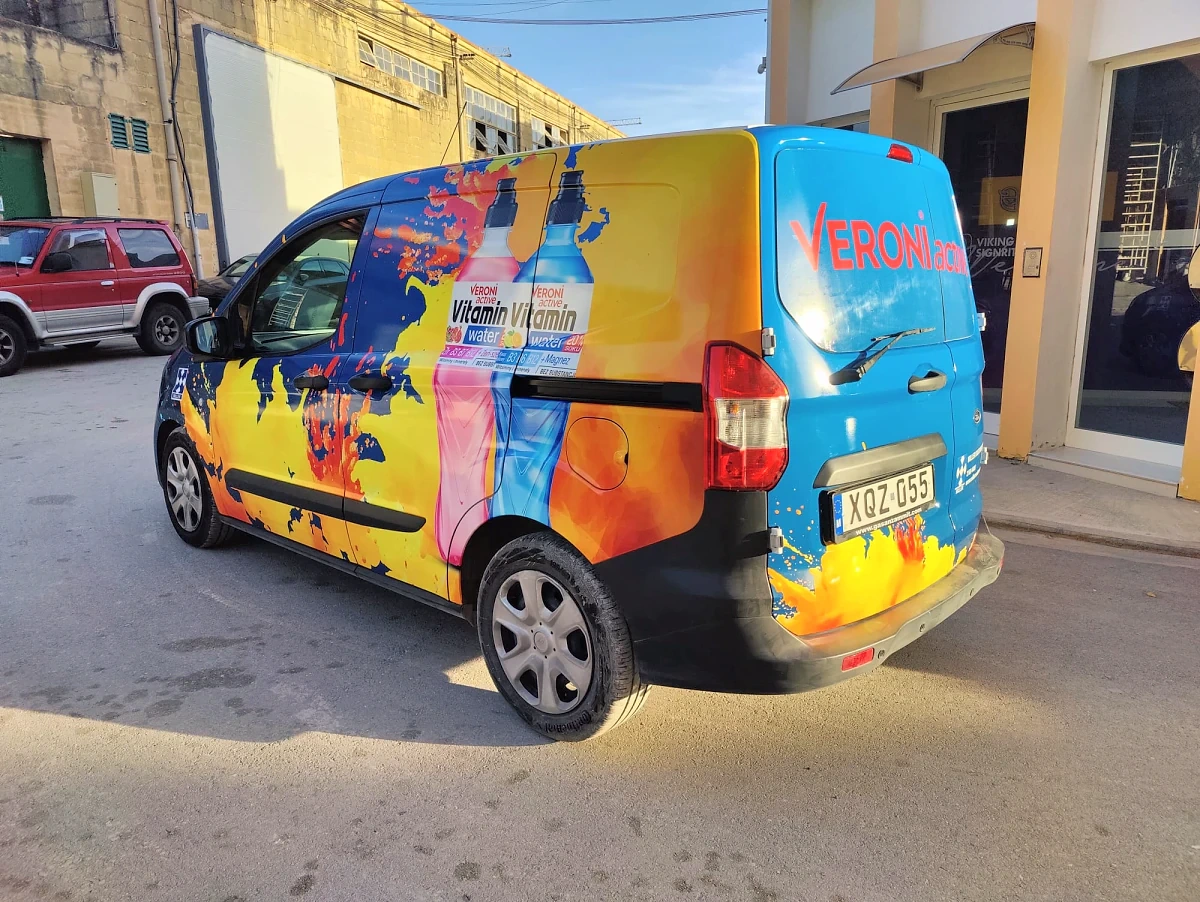 Compact van wrapped in a bright orange and blue pattern with printed drink bottles