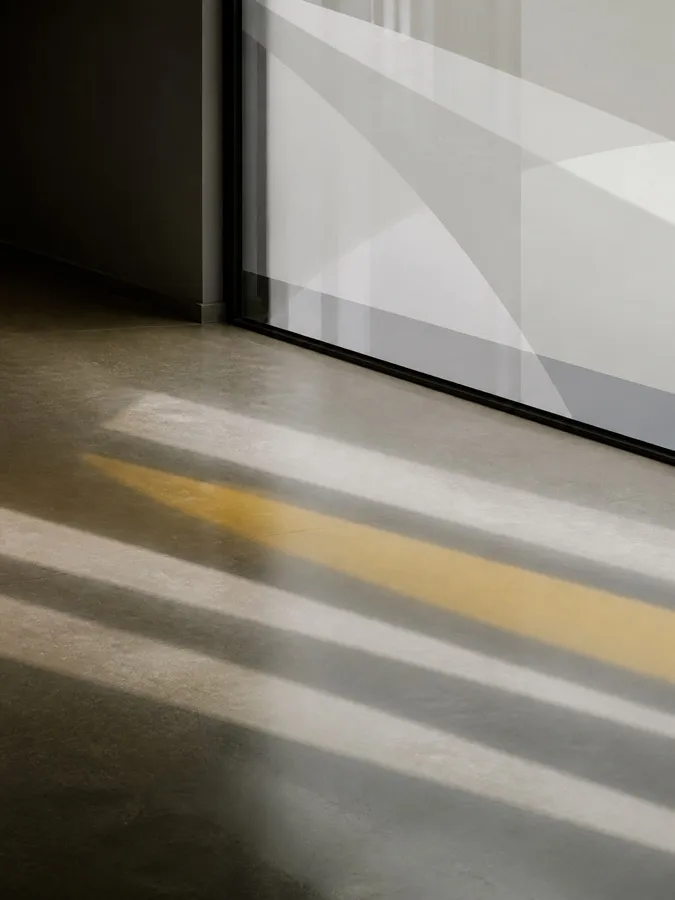 Sunlight filtered through frosted geometric window film onto concrete