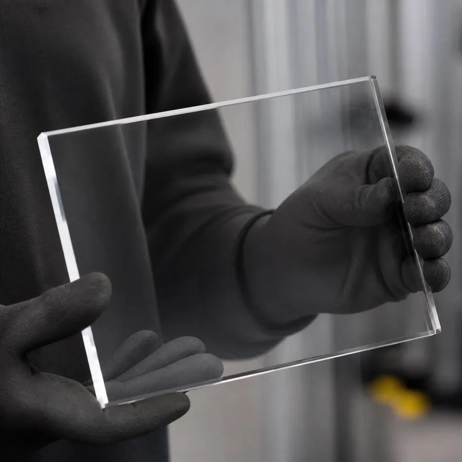 Clear finished acrylic plaque held in gloved hands under soft studio light