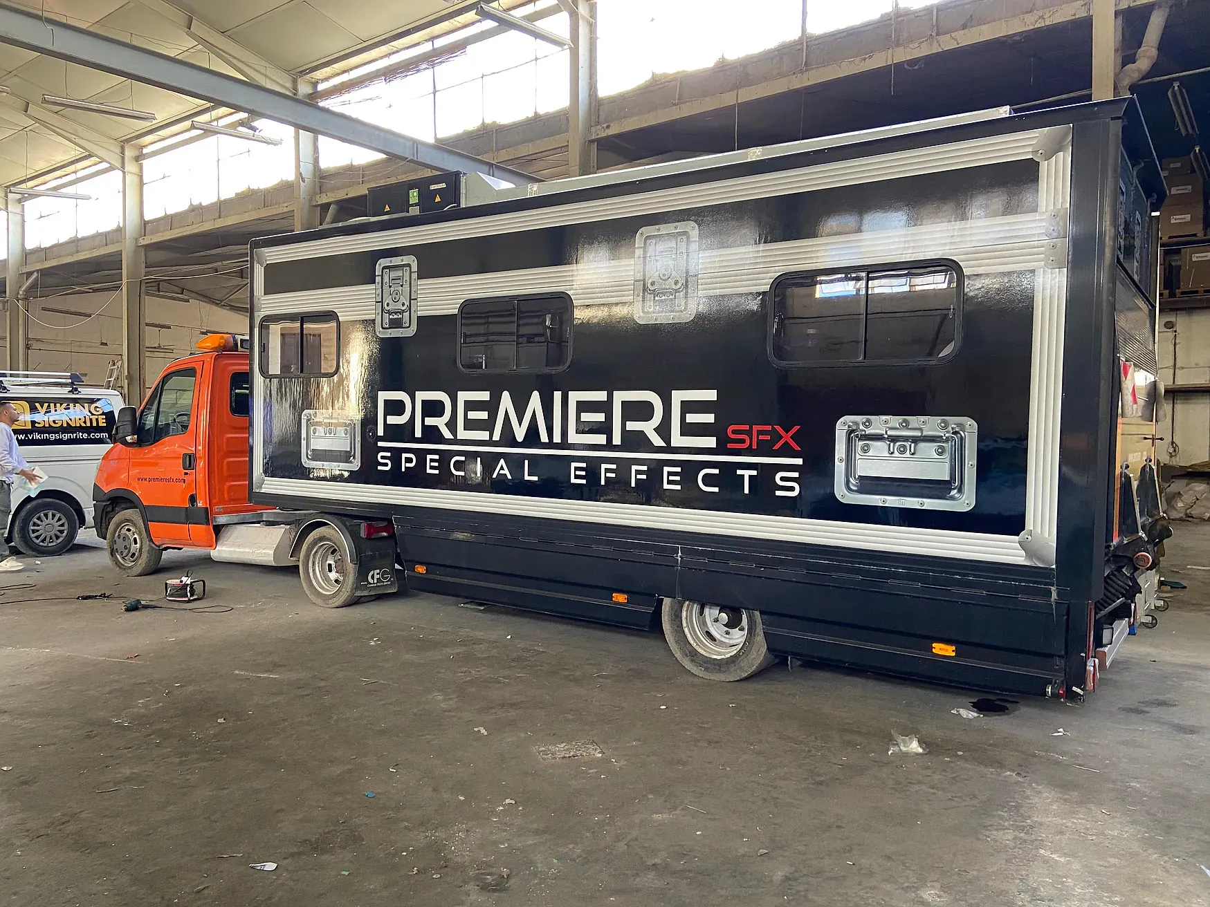 Gloss black wrapped truck body with large white and red lettering, photographed side-on in a workshop
