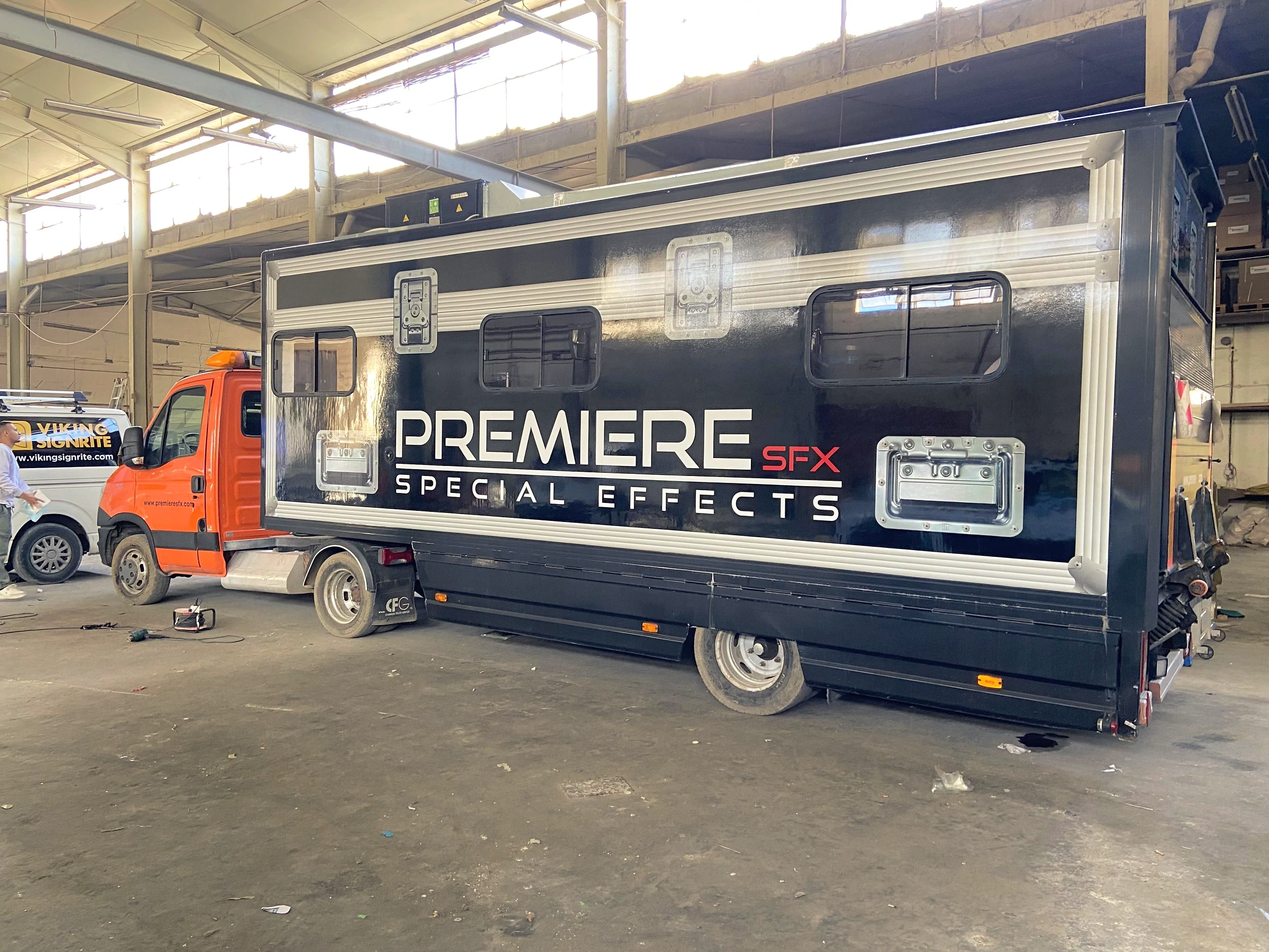 Gloss black wrapped truck body with large white and red lettering, photographed side-on in a workshop