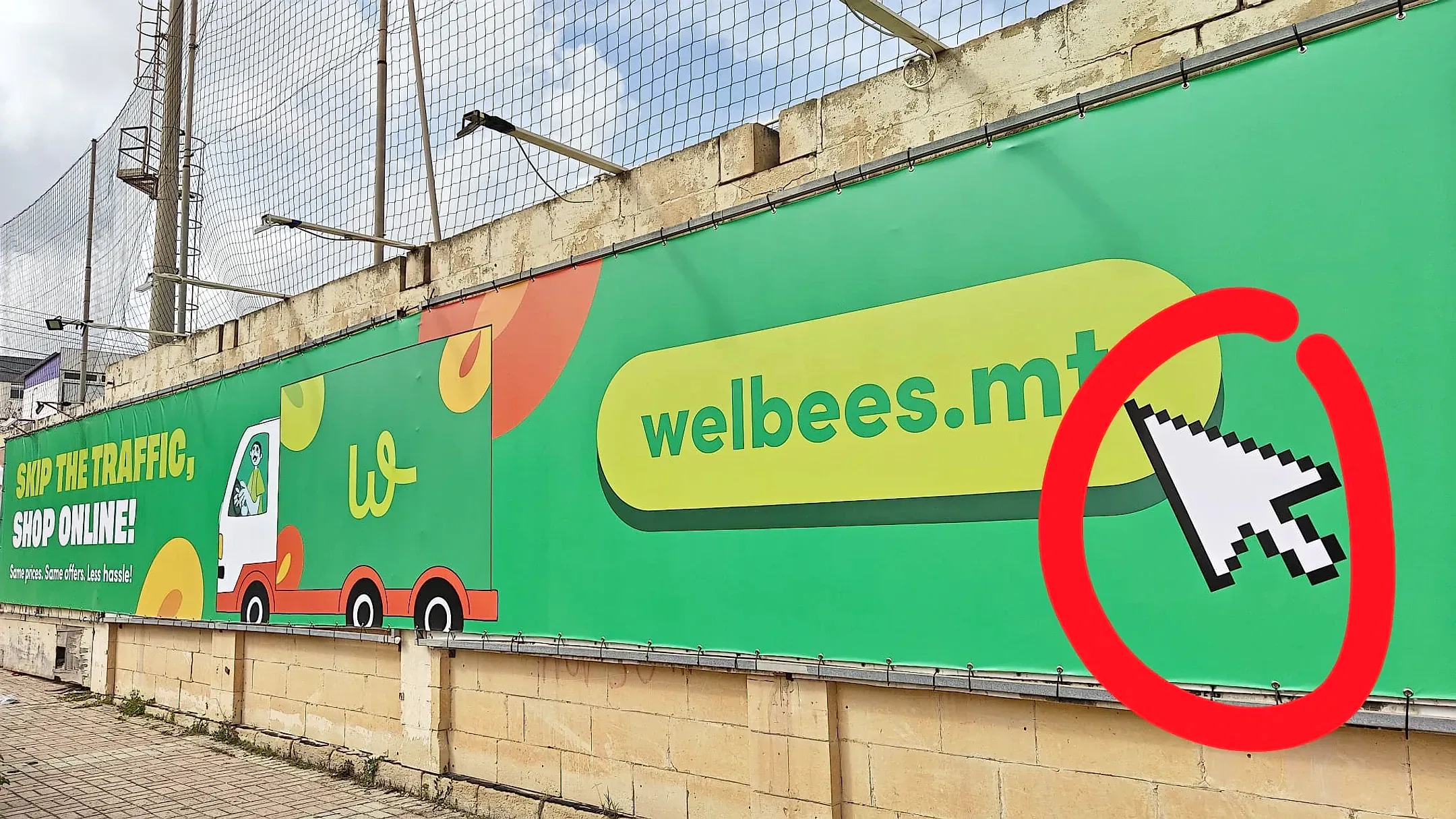 Long printed hoarding banner tensioned along a wall, showing a delivery van illustration and a web address