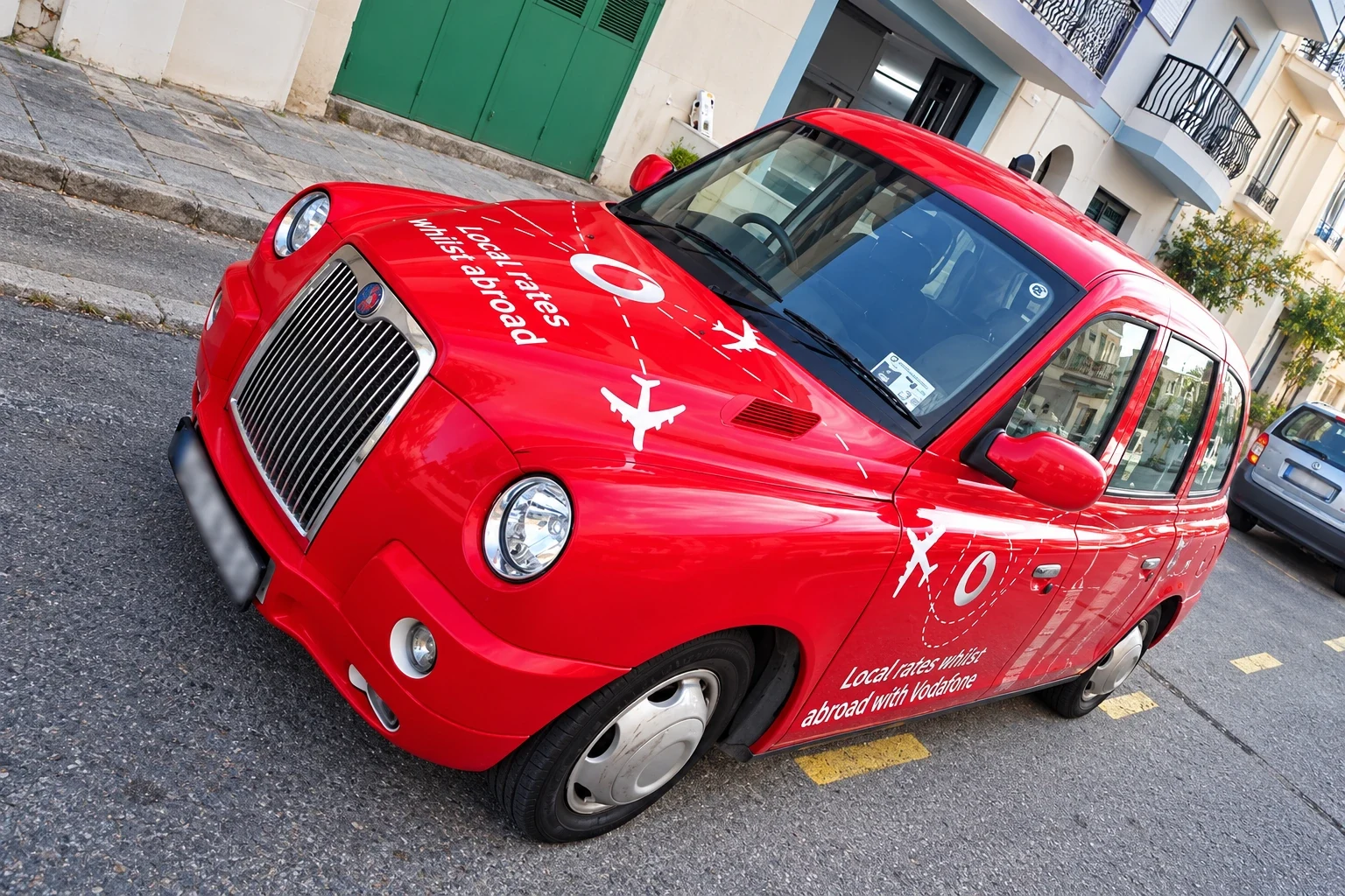 Red taxi with printed white graphics wrapped along its side and doors