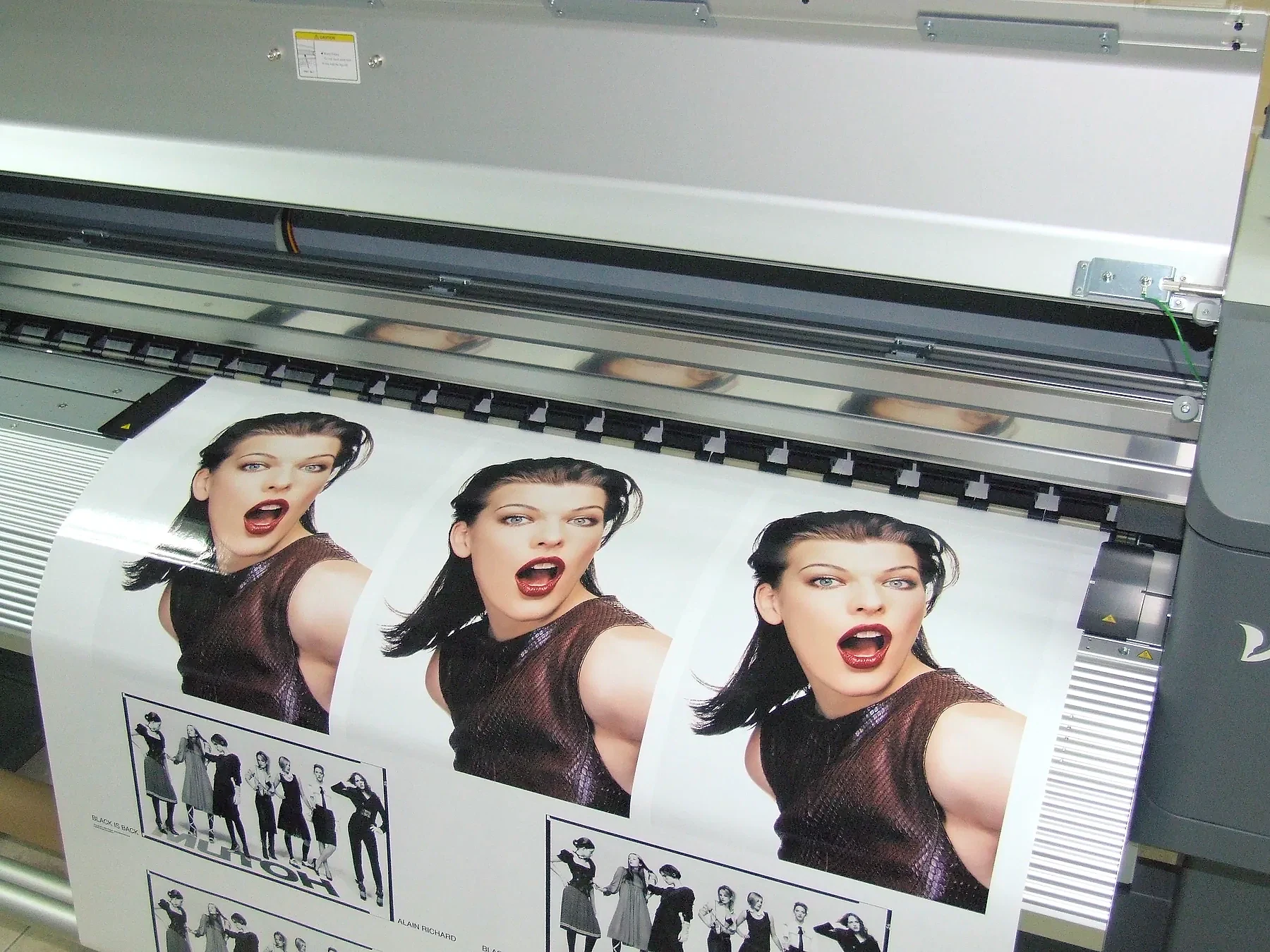 Wide-format printer running a colour print onto roll media in a production workshop