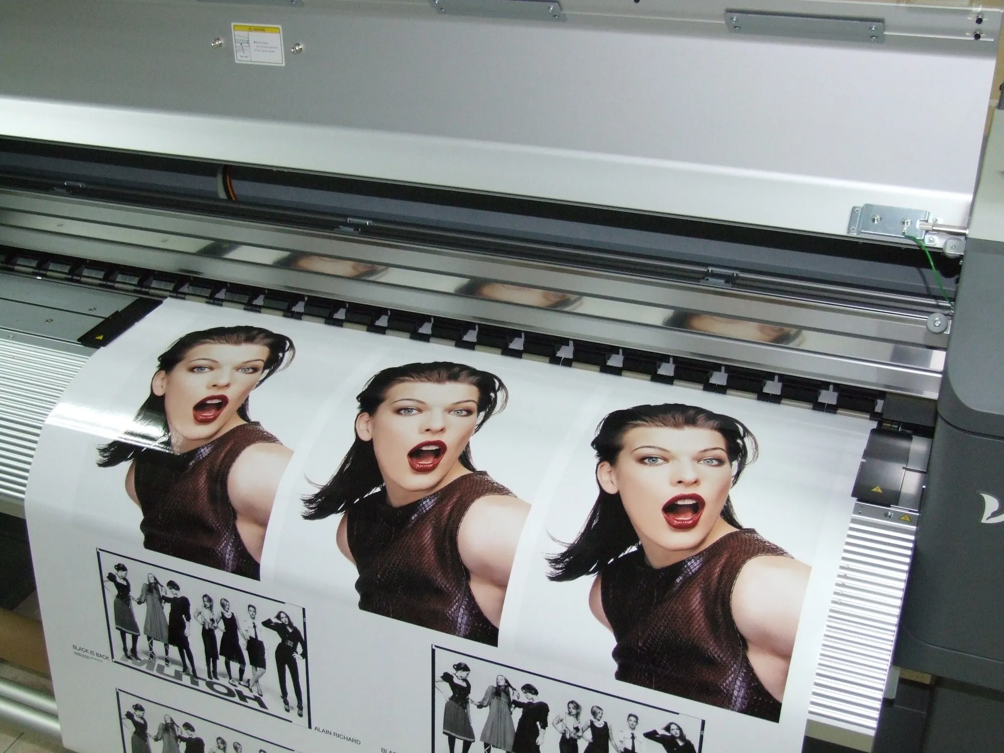 Wide-format printer running a colour print onto roll media in a production workshop
