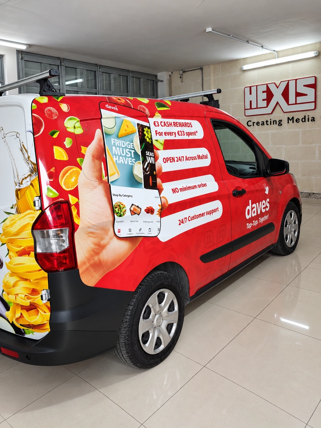 Red panel van wrapped with photographic food artwork and printed promotions, parked inside a showroom