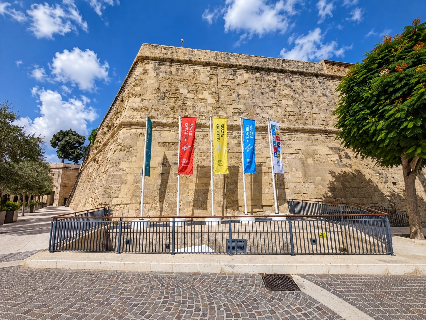 Row of colourful printed banner flags on poles in front of historic stone bastion walls