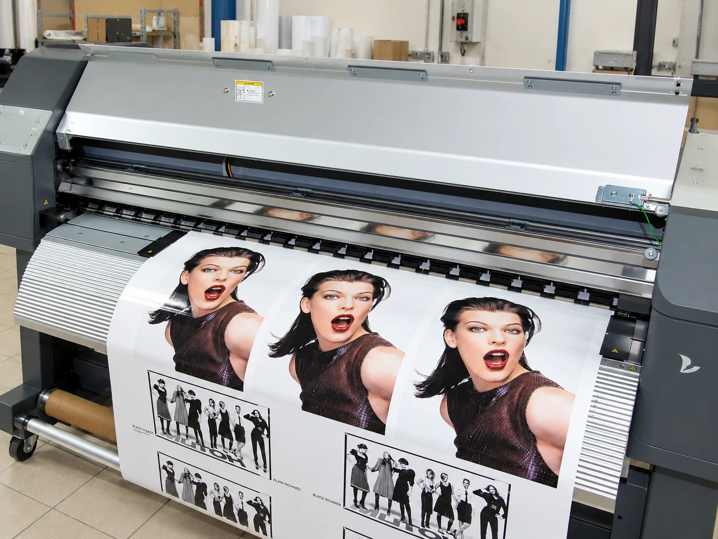 Wide-format printer running a colour print onto roll media in a production workshop