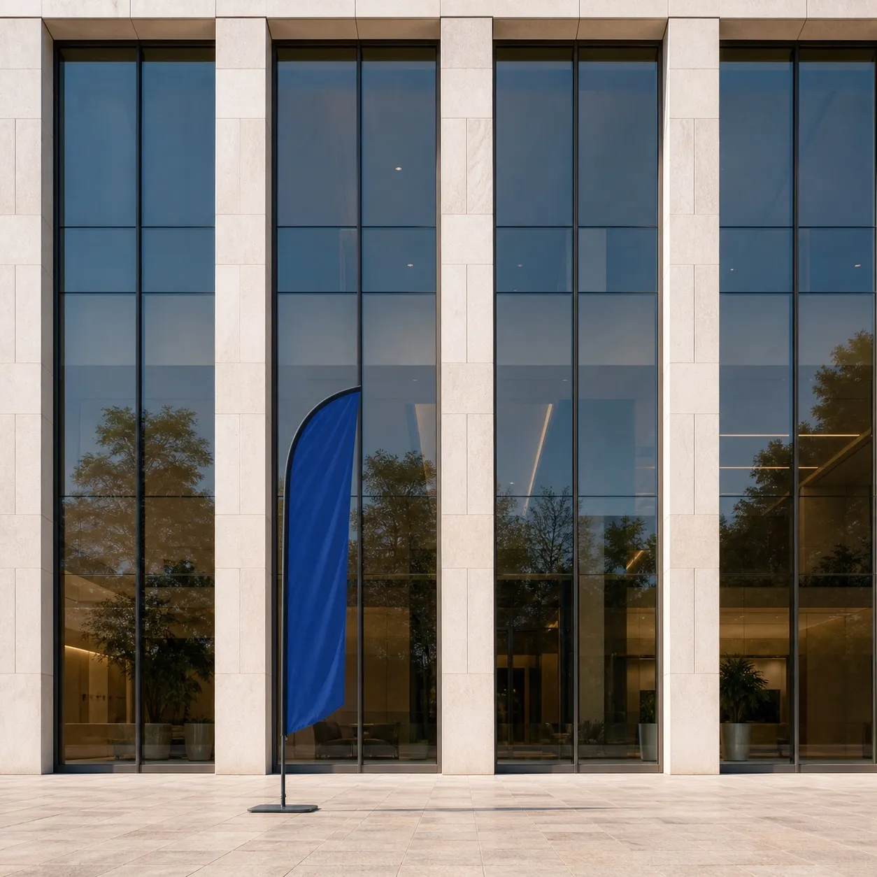 Plain blue feather flag in front of a solar-control glazed facade with layered reflections