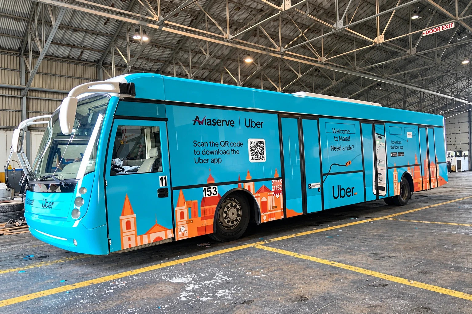 Side view of the turquoise wrapped bus inside a depot, showing the illustrated skyline along its full length