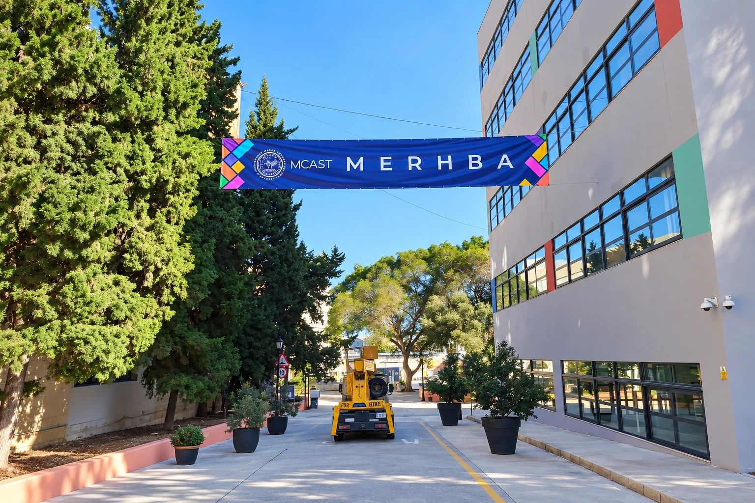 Purple welcome banner strung across a campus road between trees and a multi-storey building