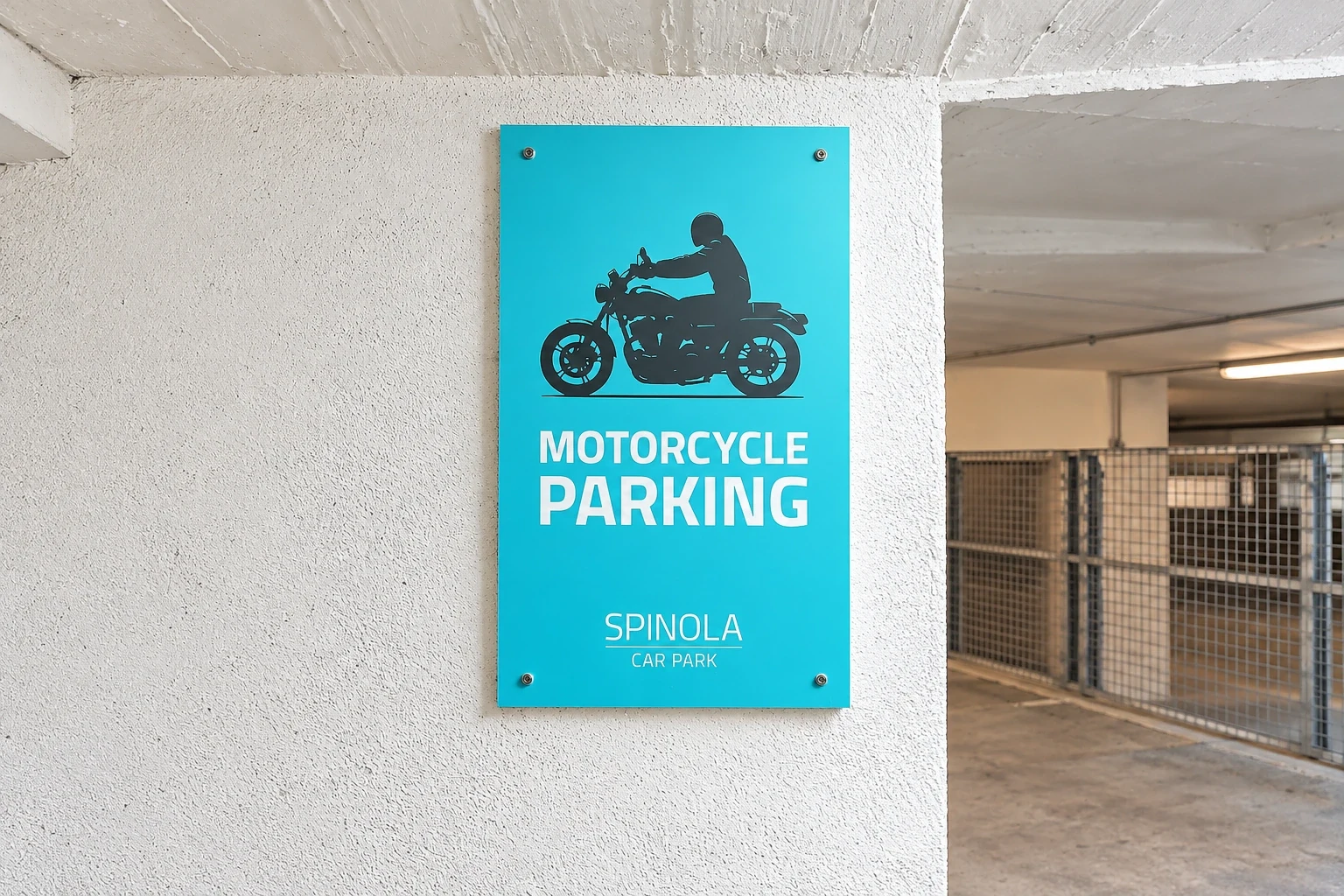 Turquoise motorcycle parking sign screw-fixed to a white concrete car park wall