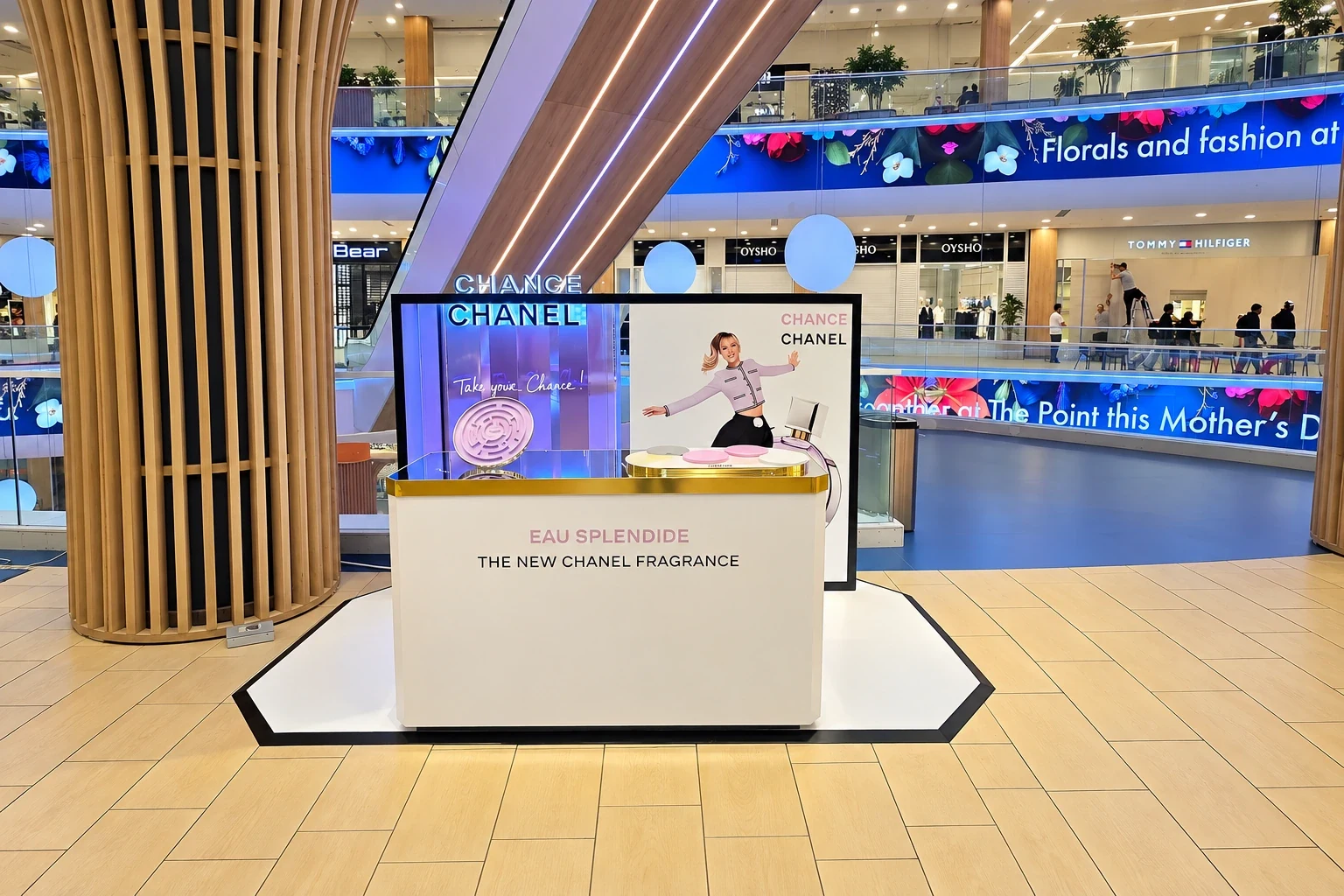 White and gold promotional podium with a printed back panel standing in a shopping centre atrium