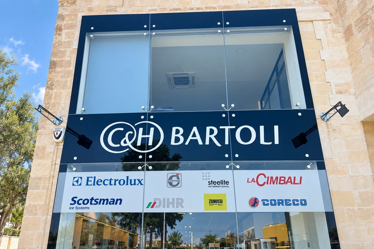 Dark fascia sign with large built-up lettering above a white panel of supplier logos on a glazed frontage