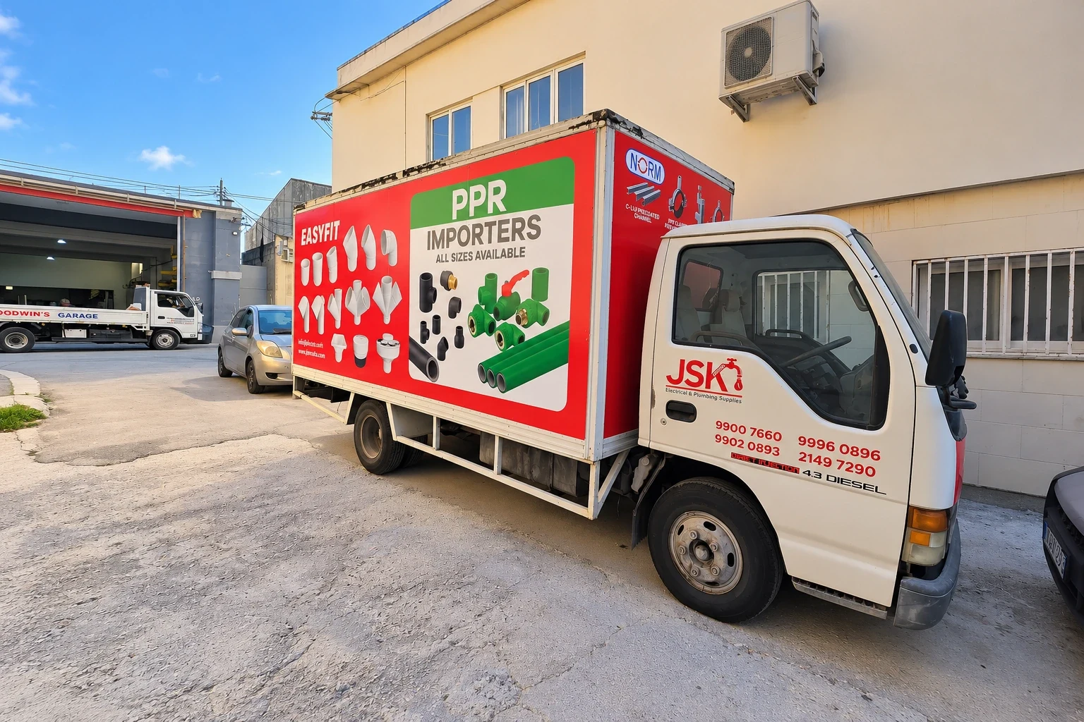 White box truck with a red and green printed panel of plumbing fittings along its body