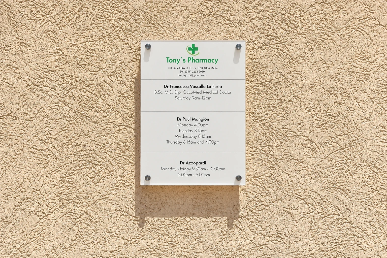 Clear acrylic plaque listing pharmacy consulting hours fixed to a stone wall on standoffs