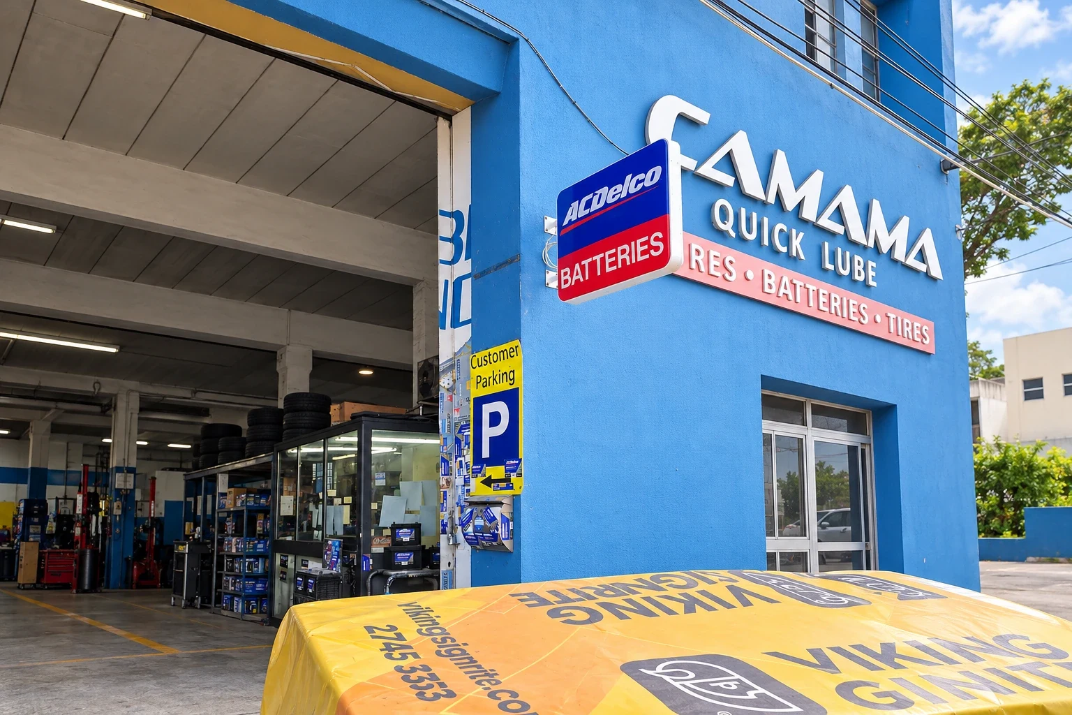 Blue projecting battery sign and a parking plate fitted to a blue workshop frontage above a covered bench