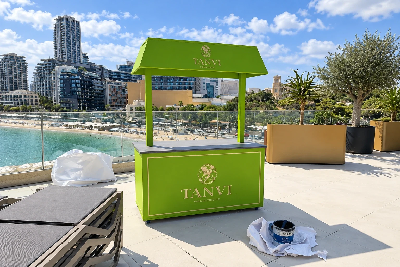 Green branded kiosk with a canopy standing on a hotel terrace overlooking a bay