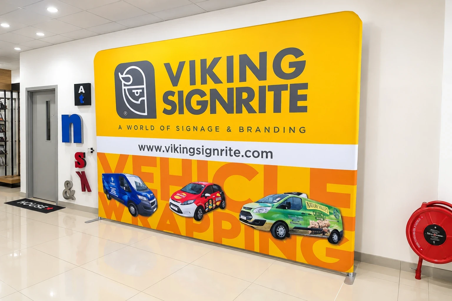 Yellow Viking Signrite fabric display wall showing three wrapped vehicles, standing in the workshop